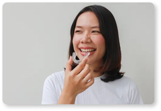 a woman smiles as she puts in a Clear Aligner