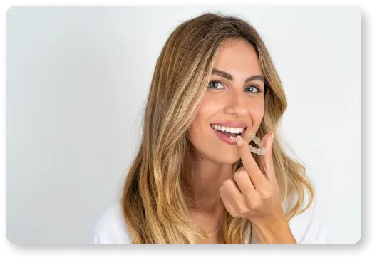 a woman is smiling and holding a retainer in her hand